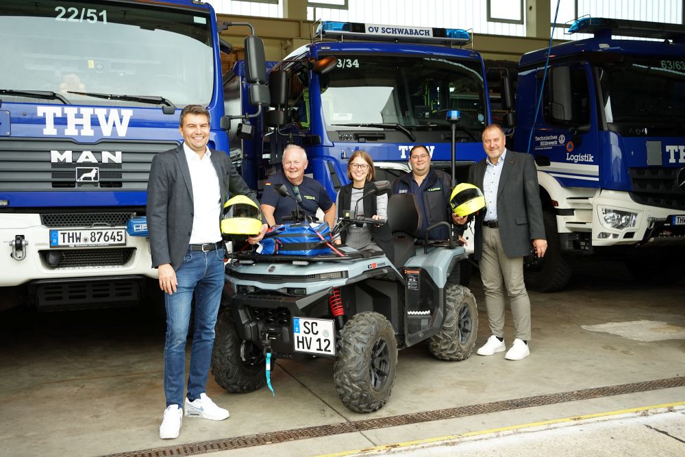 Menschen vor THW Fahrzeugen und Quad